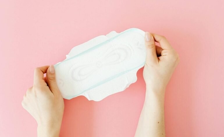 Person holding a sanitary napkin highlighting the importance of menstrual care